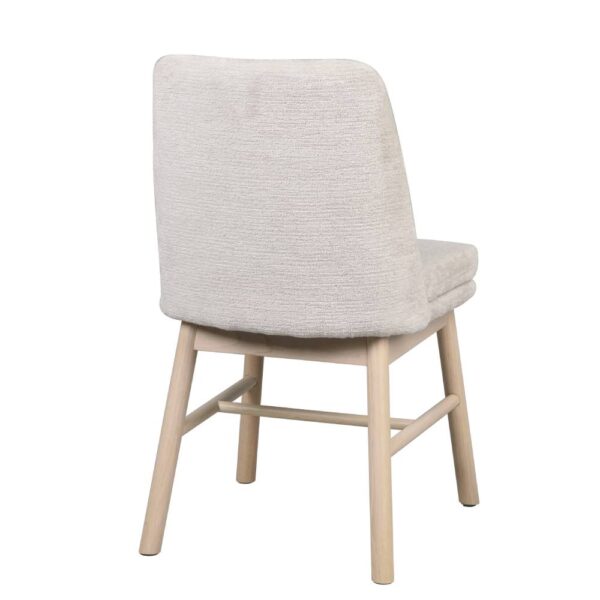 Baksida på Amesbury stol från Rowico. Stolen är klädd i ett mjukt ljusbeige tyg med fin struktur. Ben av vitpigmenterad lackad ek.