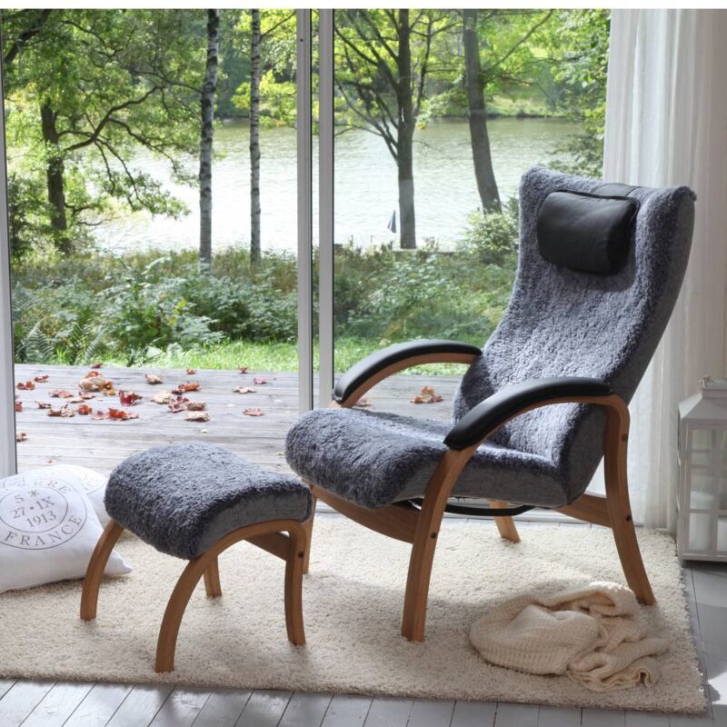 Miljöbild med Conforms Easy fåtölj och pall med klädd arm, fårskinn Graphite med ekstomme.